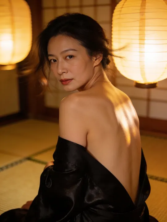 Woman with a black silk kimono slipped to her elbows looking over her shoulder