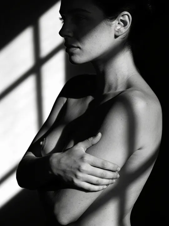 Black and white study of a woman's torso in profile with an arm across her chest