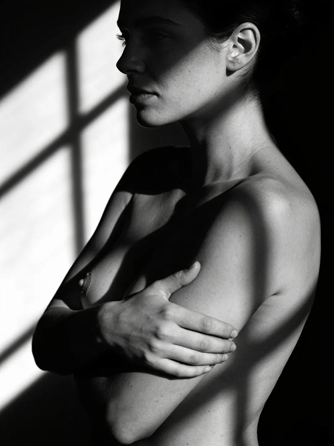 Black and white study of a woman's torso in profile with an arm across her chest